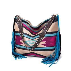 Close-up of bohemian woven tote featuring tribal patterns, fringes and leather strap