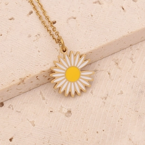 Detailed shot of golden daisy pendant with white enamel petals and yellow center