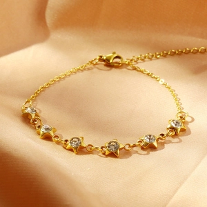 Détail macro du bracelet étoile doré avec zircons sur un tissu en satin rose