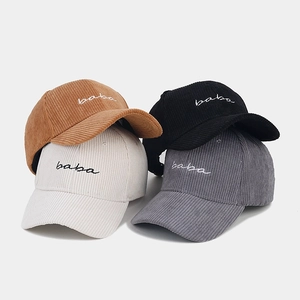 Stack of corduroy baseball caps featuring baba embroidery in brown, black, grey and white