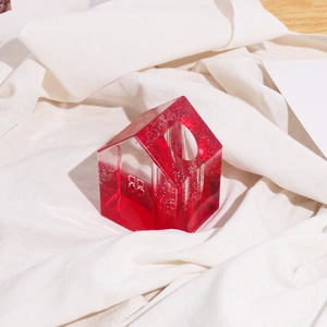 Dettaglio macro del vaso in resina a forma di casa con design bicolore rosso e trasparente