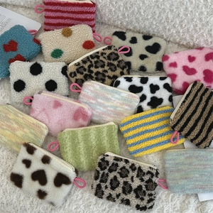 Close-up of plush cosmetic bags in leopard, cow, and polka dot prints on a soft rug