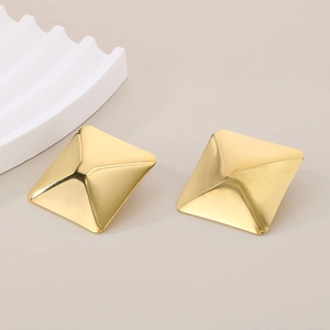 Detailed view of square gold pyramid stud earrings with polished metallic surface and texture