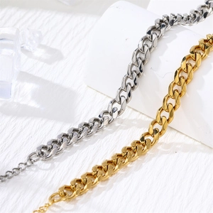 Detail of silver and gold Cuban link chains laid diagonally on a textured white surface