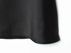 Detailed macro shot of black satin dress fabric showing premium texture and stitching
