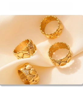 Detail of four 18K gold plated heart rings with diamond inlay on beige fabric