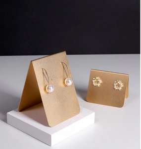 Macro detail of gold pearl earrings on a minimalist display stand with sharp details