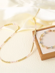Detail of beaded necklace with clear crystal beads and tri-color gold plated bracelet
