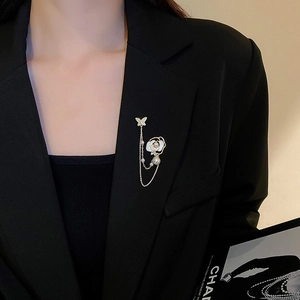 Détail d'une broche fleur dorée avec perles et pompons sur une veste de costume noire