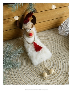 Close-up of plush reindeer ornament with red hat on woven mat in festive scene