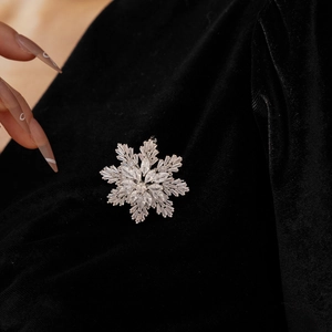 Detailed close-up of sparkling snowflake brooch with zircons on black velvet background