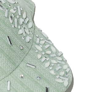 Detail view of mint green velvet fabric with intricate crystal and rhinestone embellishments