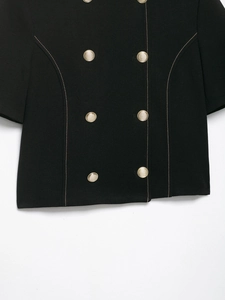 Close-up of black short jacket with gold double-breasted buttons and contrast stitching