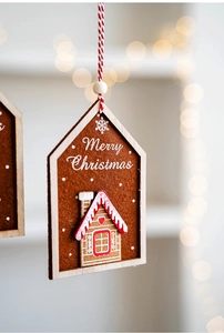 Close-up of wooden house-shaped felt ornament with Merry Christmas text and gingerbread house