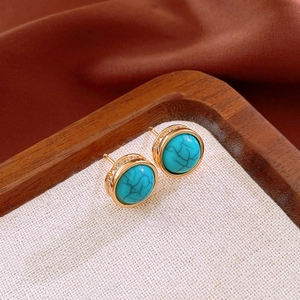 Detail of round turquoise earrings with gold rim and small zircon stones on side