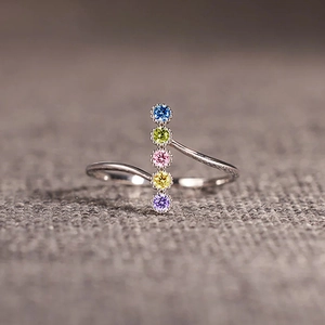 Detailed close-up of a silver open ring with five vertical multi-colored round gemstones