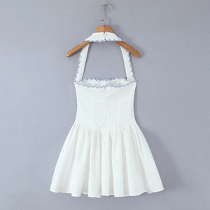 Detail of white halter mini dress with blue scalloped embroidery and pleated skirt hem