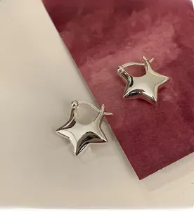 Dettaglio macro di orecchini a cerchio in argento a forma di stella con finitura lucida