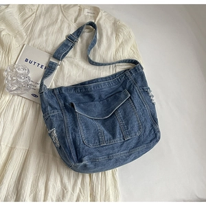 Vue à plat d'un sac cabas en jean bleu avec bords effilochés et large bandoulière réglable