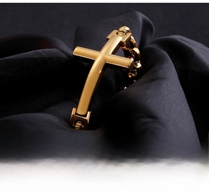 Macro detail of polished gold-tone cross bracelet on black silk with luxury texture