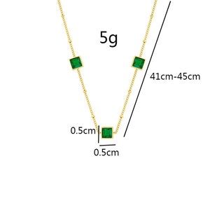 Detail view of a gold titanium necklace with three square green gemstone pendants