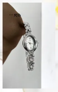 Macro detail of silver camellia bracelet watch with oval dial and diamond accents