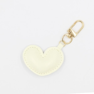 Detail of cream PU leather heart keychain with golden metal clasp and fine stitching