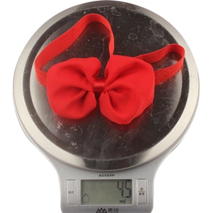 Detail of red chiffon bow headband on a scale showing lightweight 4.5g weight