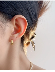 Close-up of elegant gold C-shaped earring on model showing polished metallic finish