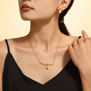 Golden bow pearl earrings and necklace set with a diamond ring on a female model