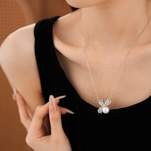 Détail du collier pendentif nœud argenté avec perle blanche et zircons sur mannequin