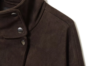 Détail du col d'une veste en daim marron foncé avec boutons métalliques ronds