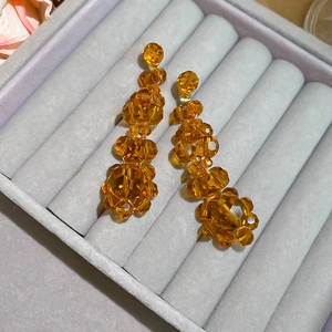 Macro detail of amber crystal flower tassel earrings in a grey velvet jewelry box