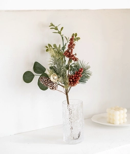 Close-up of Christmas decorative branch with red berries and pine cones in glass vase