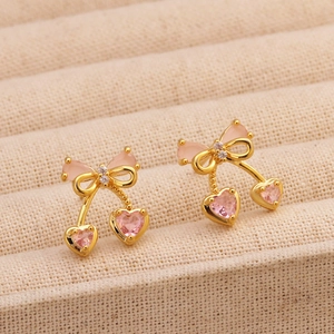 Dettaglio macro di orecchini a ciliegia placcati oro 18K con zircone rosa e fiocco