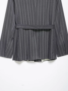 Close-up of grey pinstripe blazer featuring back waist tie belt and woven texture details