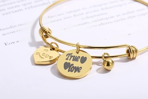 Macro-opname van hartbedels aan een gepolijste roestvrijstalen armband in gouden kleur