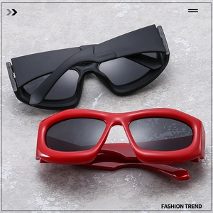 Top view of chunky Y2K style sunglasses in black and red on a grey stone texture background