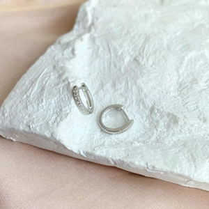 Close-up of S925 sterling silver hoop earrings with cubic zirconia on white stone