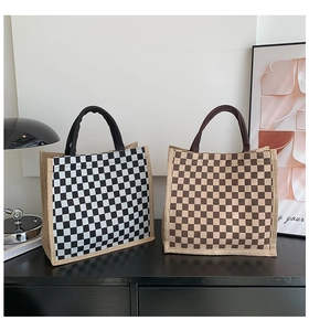 Detailed view of woven checkerboard tote bags in black and brown on a minimalist shelf