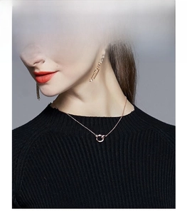 Détail du collier à double anneau entrelacé or rose et des boucles d'oreilles assorties