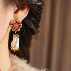 Close-up of vintage flower earring with pink gemstone and white baroque pearl on model