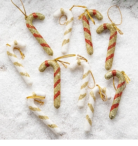 Detail of red and white candy cane ornaments with gold glitter finish on fake snow