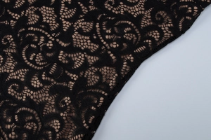 Gros plan détaillé sur la dentelle florale noire avec une doublure beige clair
