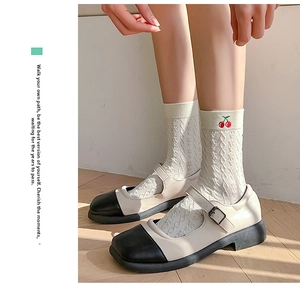 Close-up of white cable knit socks with red cherry embroidery and Mary Jane shoes