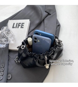 Spacious interior of shiny pleated cloud bag holding two smartphones and a lipstick