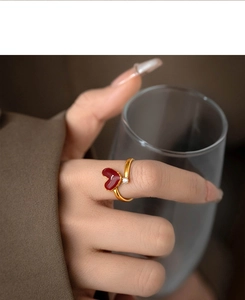 Detail of an 18k gold-plated ring with red enamel heart and zircon worn on finger