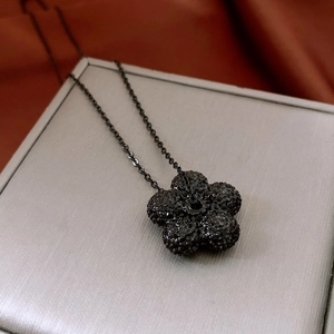 Close-up of black floral pendant necklace with pave-set crystals on a jewelry box