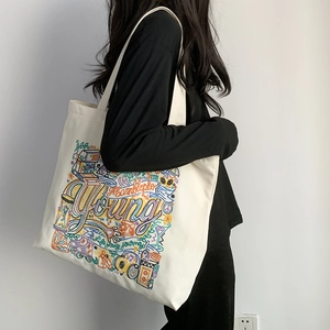 Detail of embroidered canvas tote bag with Young colorful graffiti and sturdy shoulder strap