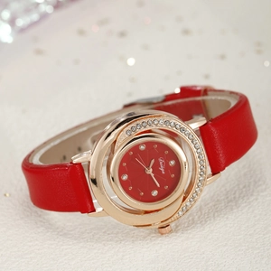 Close-up of luxury gold watch with sparkling diamond-set bezel and red leather strap